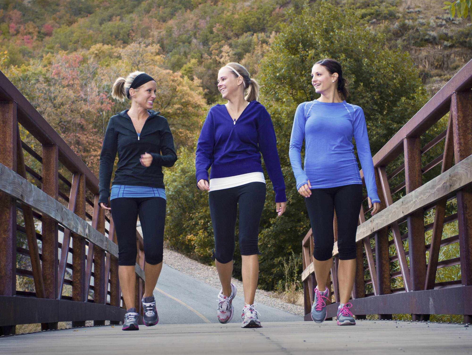 Three women walking over a bridge